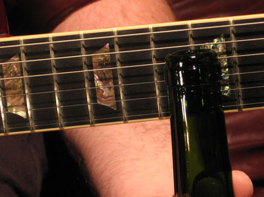 Rest the slide on the strings (not pressed down), directly over the fret wire.