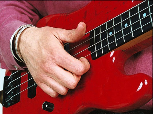 Hook your index finger under a high string, and with an opposing twist of your wrist, snap the string against the fret board.