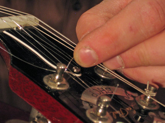 Kink (or crease) the metal wire toward the center of the electric guitar's headstock.