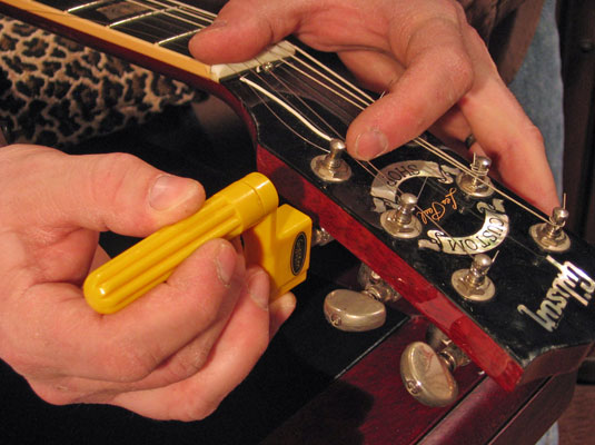 While keeping the string tight against the post with one hand, wind the tuning peg clockwise with the other hand.