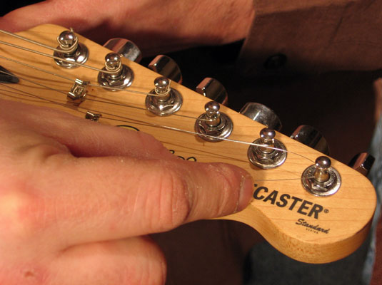 Kink (or crease) the metal wire toward the center of the electric guitar's headstock.