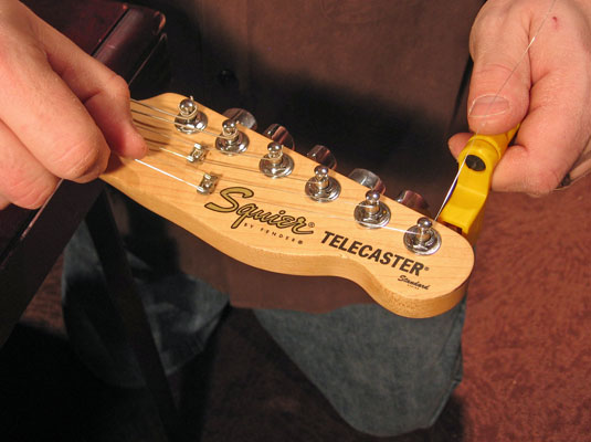 While keeping the string tight against the post with one hand, wind the tuning peg clockwise with the other hand.
