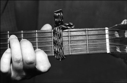 A capo on the guitar neck. Notice that the capo sits just before the fret — not directly on t