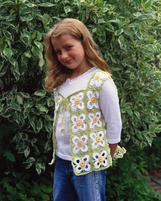 A young girl wears a crochet vest with a floral motif.