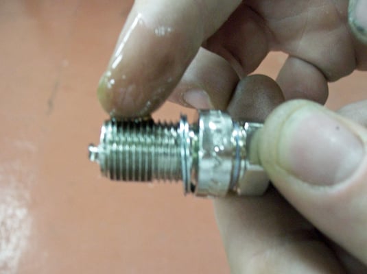 Lightly coat the threads of the spark plug with a dab of oil from the oil dipstick<i>.</i>