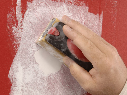 Let the patch dry completely (usually overnight), and smooth the patch with sandpaper wrapped around a sanding block.