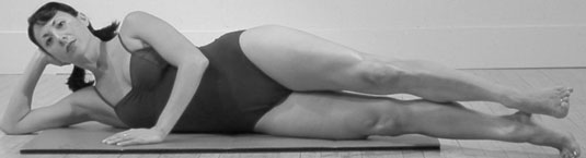 Lie on your side with your legs slightly in front of your body and slightly turned out in the Pilates First Position.