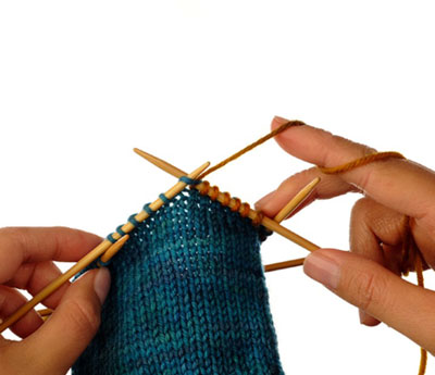 At the end of the leg, knit half of the stitches using a smooth waste yarn of a similar thickness to the working yarn.