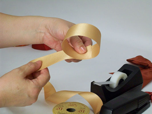 Working from the spool, make a loop of ribbon and hold it together with your thumb and forefinger.