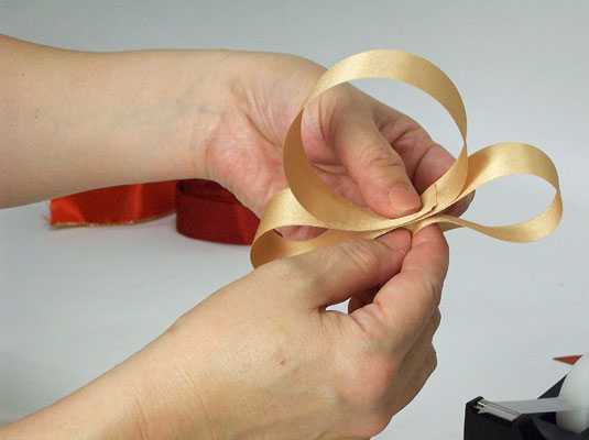 Fold the ribbon in layers under the first loop, making each layer longer than the one above it.