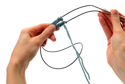 Count across half of the stitches. Carefully separate the stitches at this spot and pull about 6 to 8 inches of the cable through the opening.
