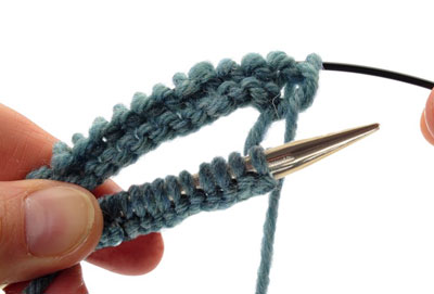 Slide the front set of stitches to the right until they are resting on the needle. Then slide the back set of stitches to the left so they are resting on the back portion of the cable.