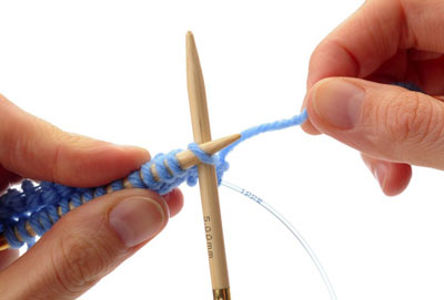 With your right hand, take the empty needle tip at the far end of the front circular needle and use it to knit the stitches on the front needle.