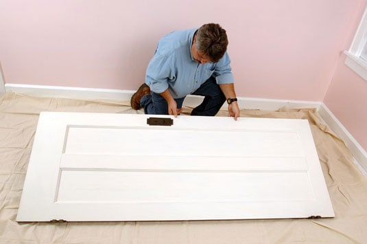 Lay the door flat on the floor, on sawhorses, or on chairs.