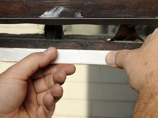 Raise the inner sash and apply a strip of weather-stripping to the bottom of the sash