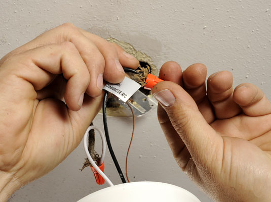 Pull the wires through the ceiling box and remove the electrical tape or wire nuts from the black (hot) wire, white (neutral) wire, and, if present, green (ground) wire.
