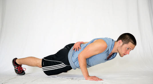 Begin to descend into your one-arm push-up, keeping your elbow in close to your side.