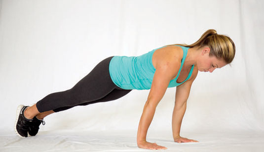 Push up off the ground into a full lockout, ensuring that the shoulders, back, and hips all rise at the same time.