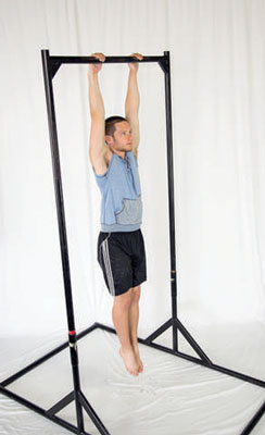 Hang from a pull-up bar (or a set of gymnastic rings) with a shoulder-width grip. Tighten everything up as if you’re in a plank position and flatten the arch out of your back.