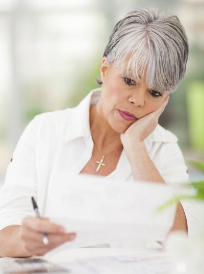 A woman reviews a document while seating in a garden.