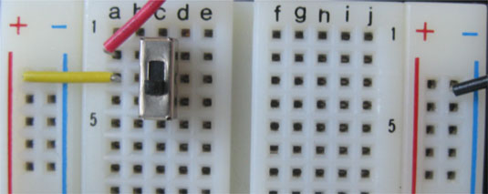 A switch connects and disconnects a battery from the power rails of a solderless breadboard.