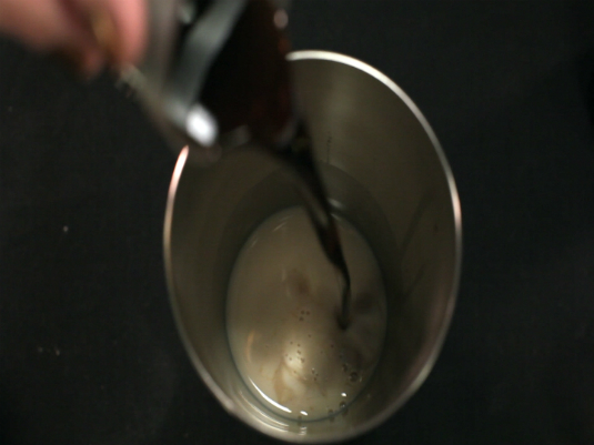 Pouring a drink into a cocktail mixer.