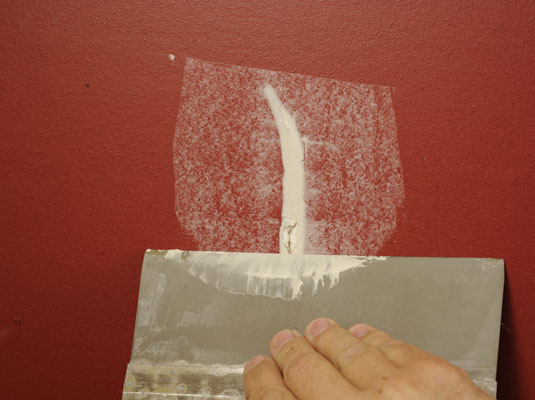 Apply a light coating of compound to the crack using the 6-inch taping knife.