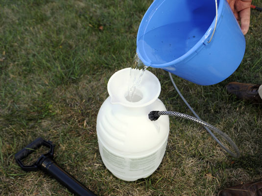 Mix the hot water, bleach, and detergent and pour into the garden sprayer.