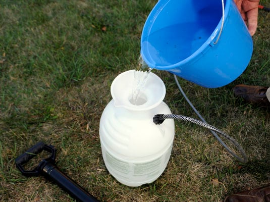 Mix the hot water, bleach, and detergent and pour into the garden sprayer.