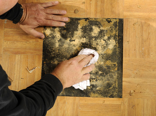 Use mineral spirits to soften the old adhesive on the floor.