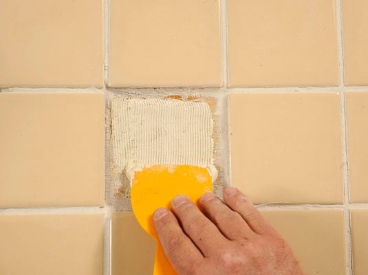 Apply adhesive to the new tile and to the floor.