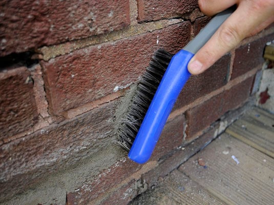 Scrub the area with a stiff brush to wipe away particles of mortar on the bricks.