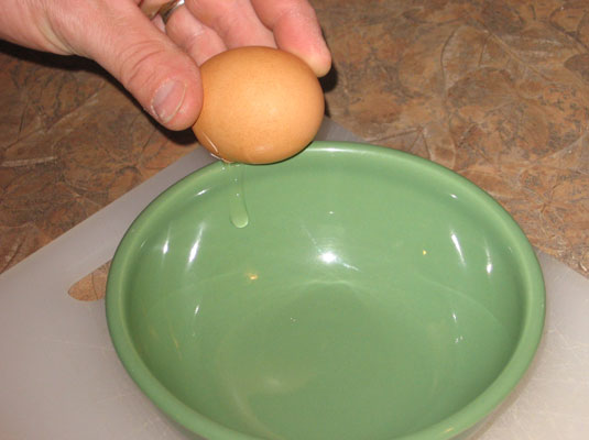 Tap the egg on the side of a small bowl or glass measuring cup.