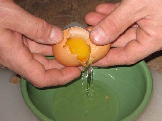 Place the tips of your two thumbs into the crack and gently open the egg so that the yolk and white fall into the bowl or measuring cup.