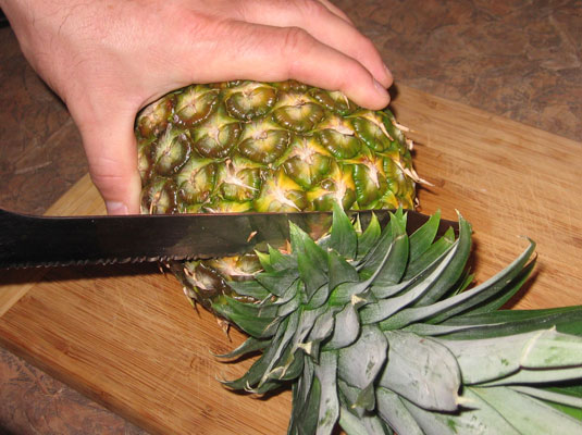 Lay the pineapple on its side on a cutting board, then cut off the top and bottom.