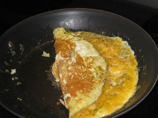 Tilt the pan away from you and use a spatula to gently fold a third of the omelet on itself.