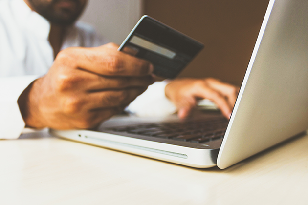 Man holding credit card typing on laptop