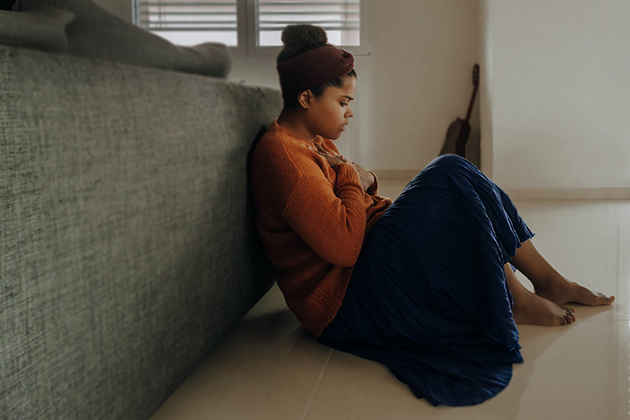 Woman sitting on the floor with an anxious expression