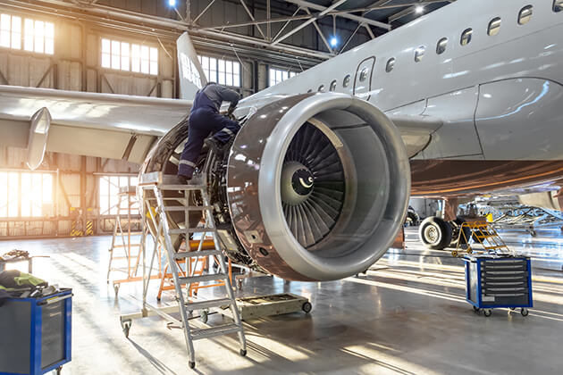Phot of man performing maintenance on an airplane engine