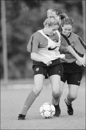 A soccer player shields the soccer ball from an opponent.