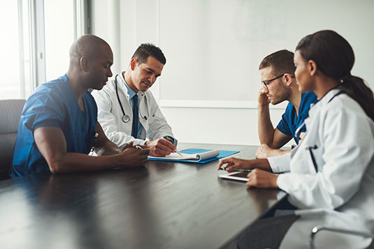 four doctors sitting around conference table