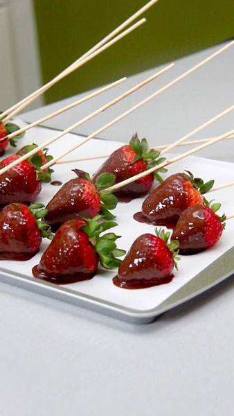 Place the dipped strawberries on the prepared sheet tray to chill.
