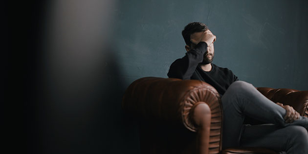 Man sitting in chair with his head in his hand