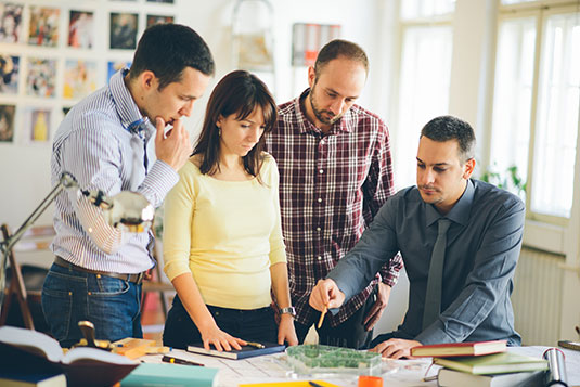 Four colleagues standing around desk discussing project