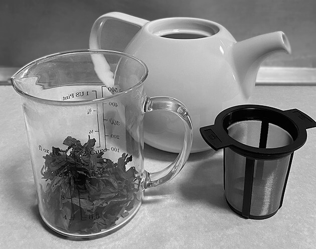 Photo showing a teapot, tea leaves, and a basket filter